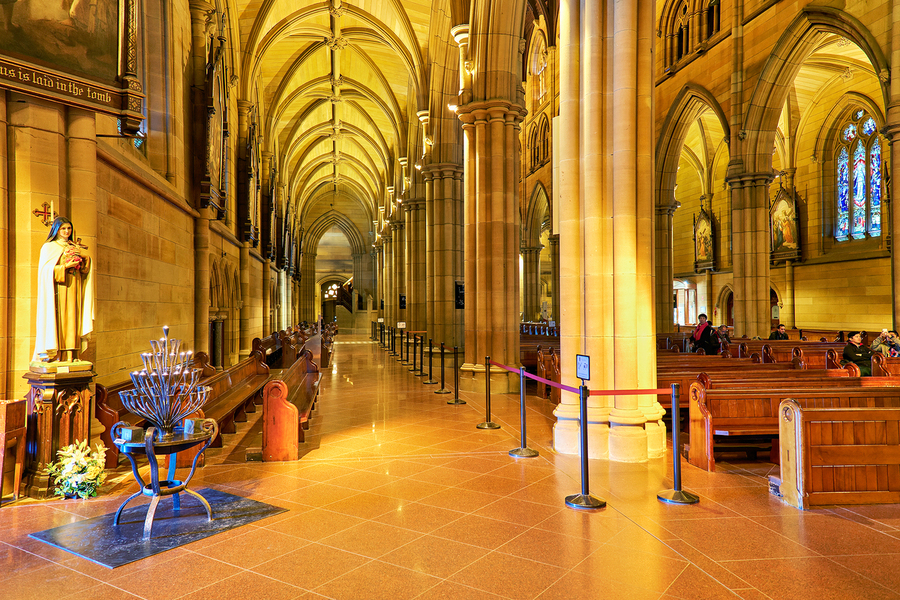 Interior of a grand cathedral with pews and stained glass.  Print