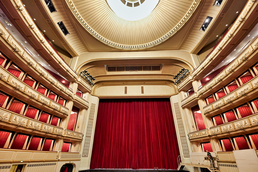 Grand opera house interior with red stage curtain and balconies.  Print