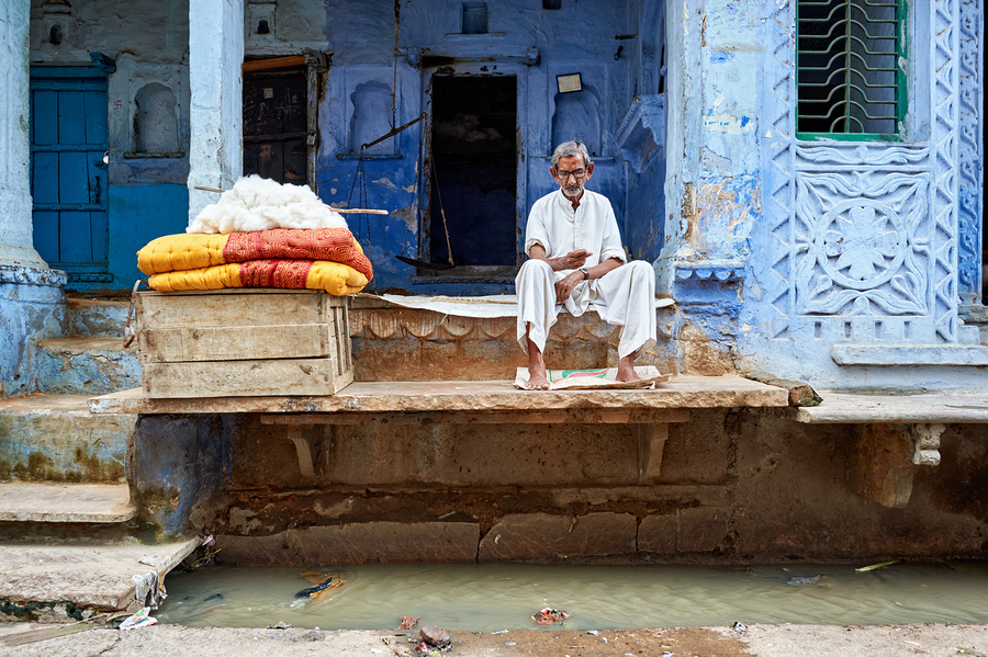 Portrait of an old man sitting by a blue building in Bundi Raja  Print