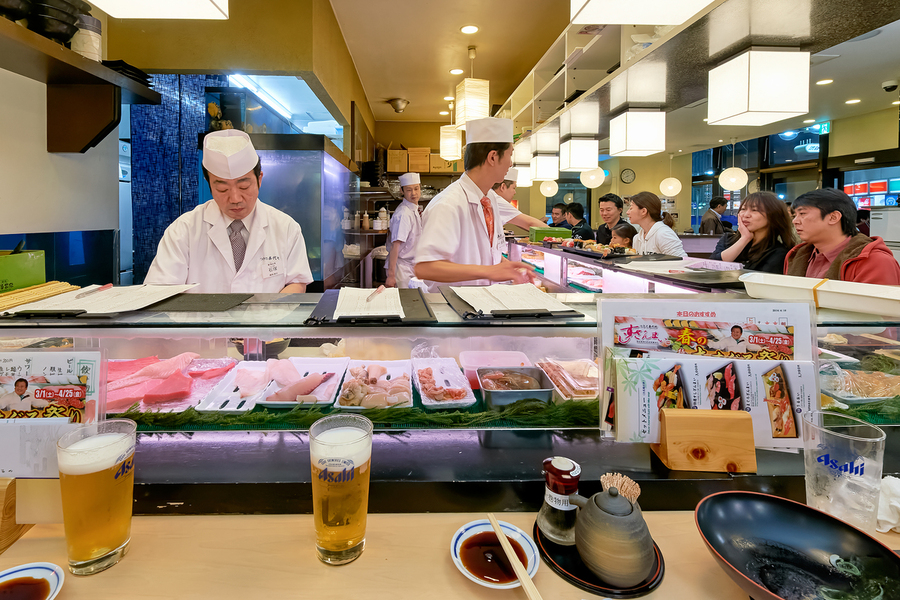 Sushi bar in Shibuya district with chefs and guests enjoying mea  Print