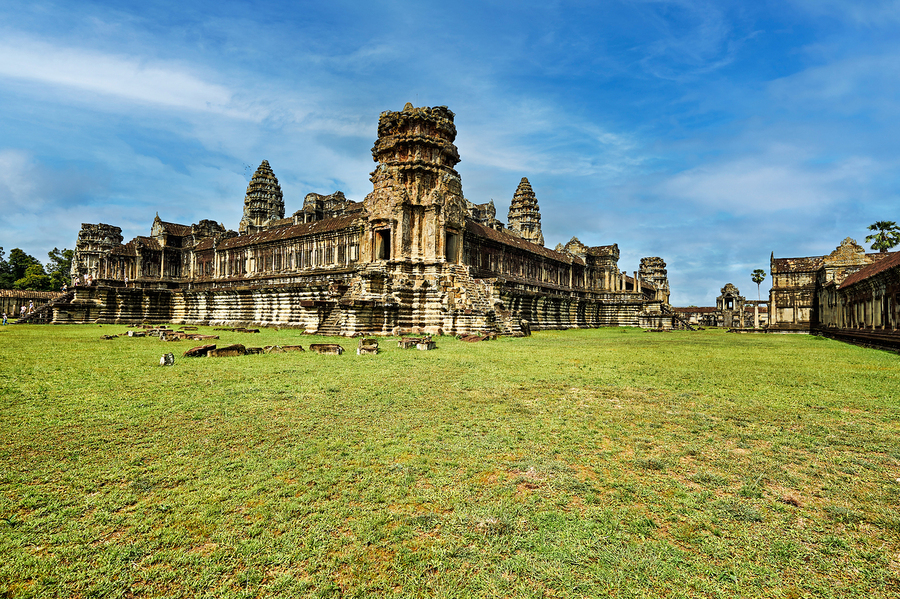 Angkor Wat temple complex with green grass and blue sky.  Print