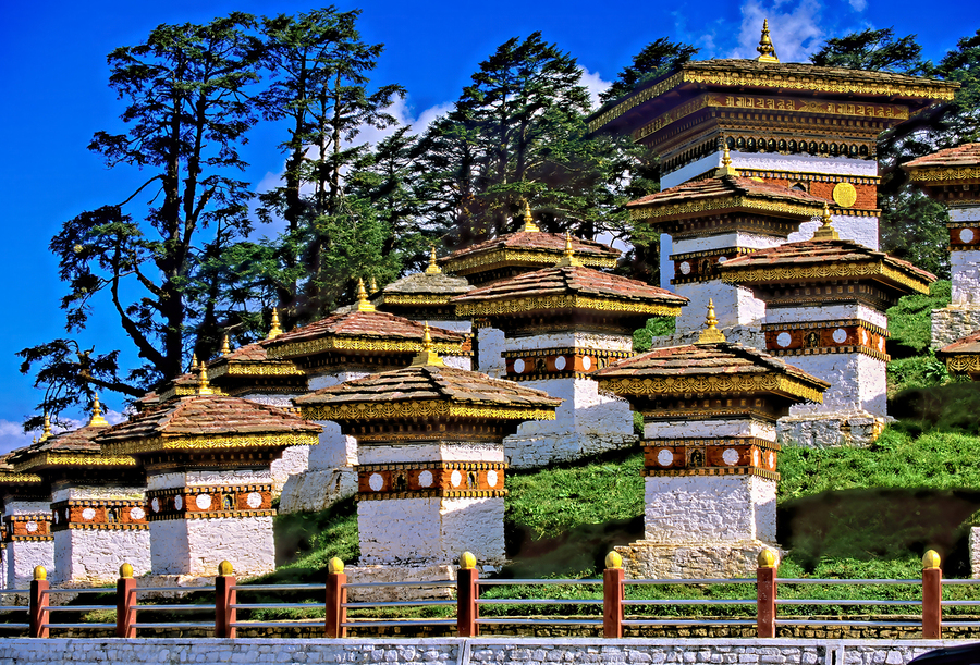 Druk Wangyal Chortens Bhutan with lush trees and blue sky.  Print