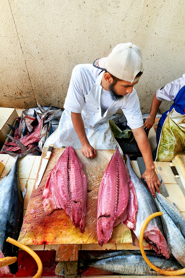 Fish market in Muscat Oman shows a vendor at work  Print