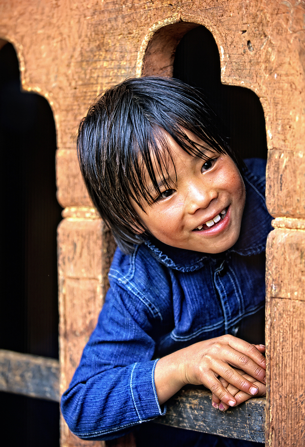 Smiling child peeking from a wooden window.  Print
