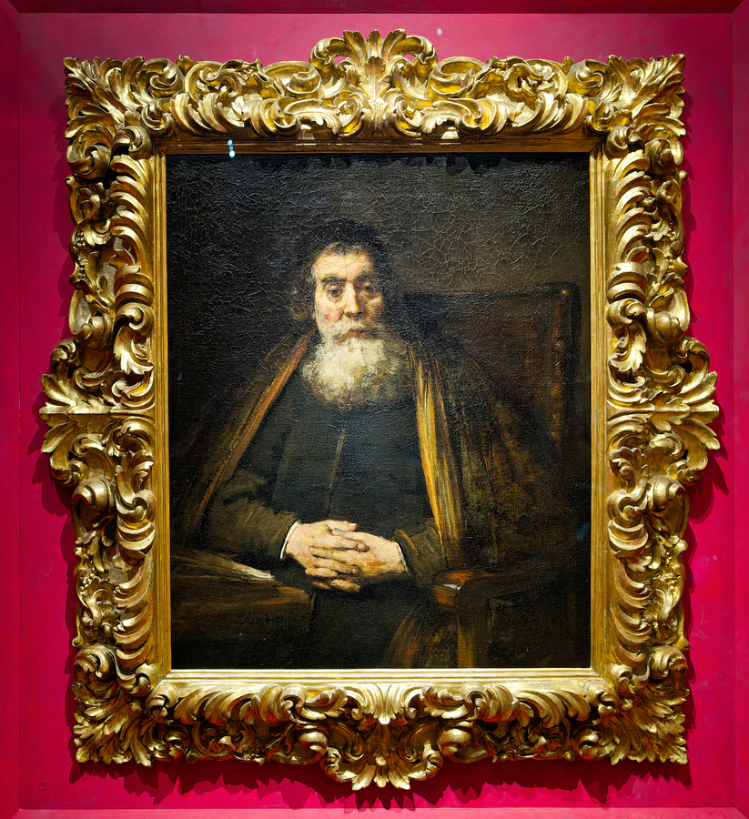 A rabbi sits calmly in a chair with hands together  Print