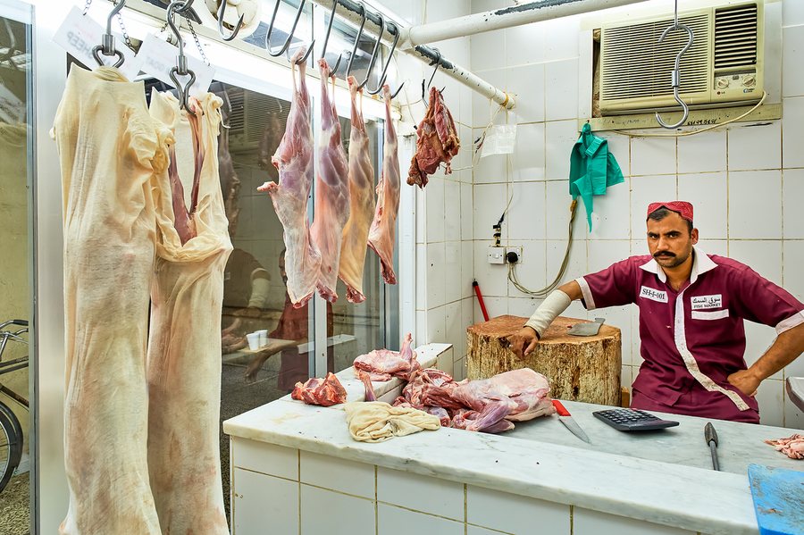 Butcher works in meat market in Dubai with hanging meat  Imprimer
