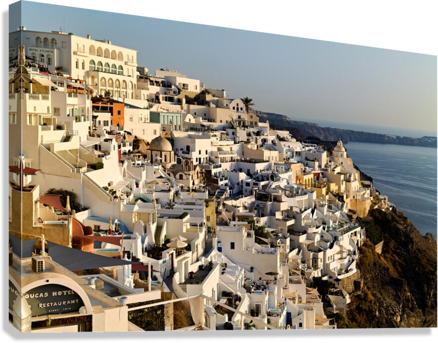 Santorinis white buildings cascade down cliff to the sea. Canvas Print