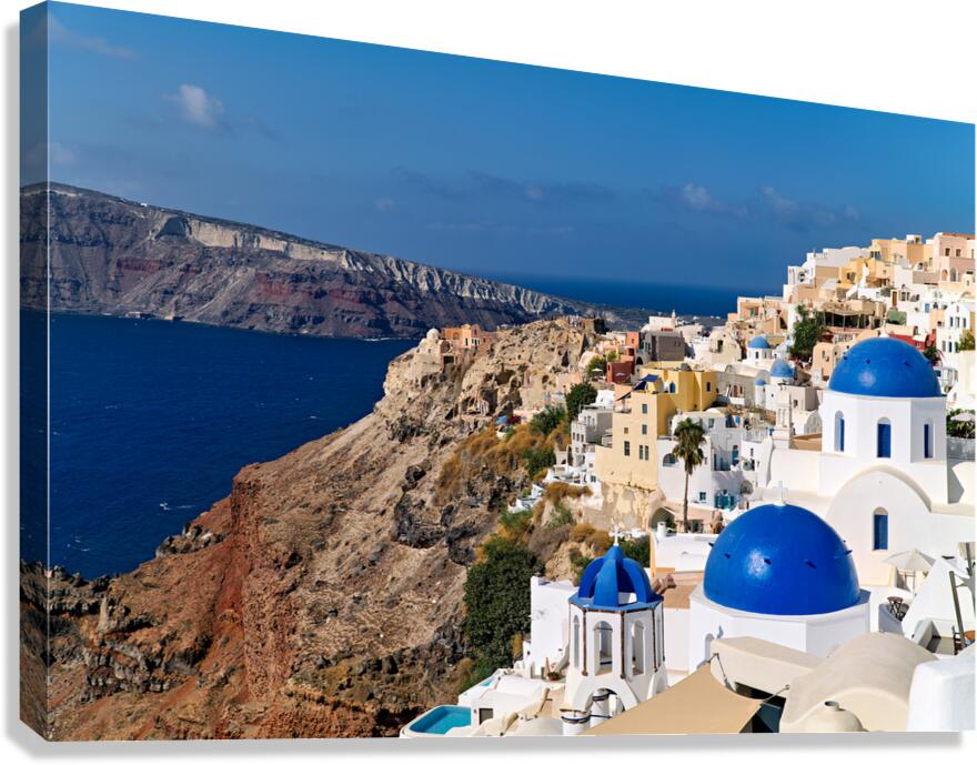 Santorinis iconic white buildings and blue domes overlooking th Canvas Print