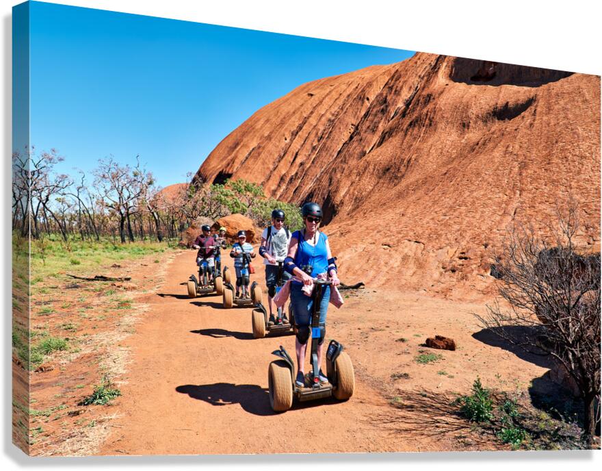 Tourists ride Segways near Uluru in Australia. Canvas Print