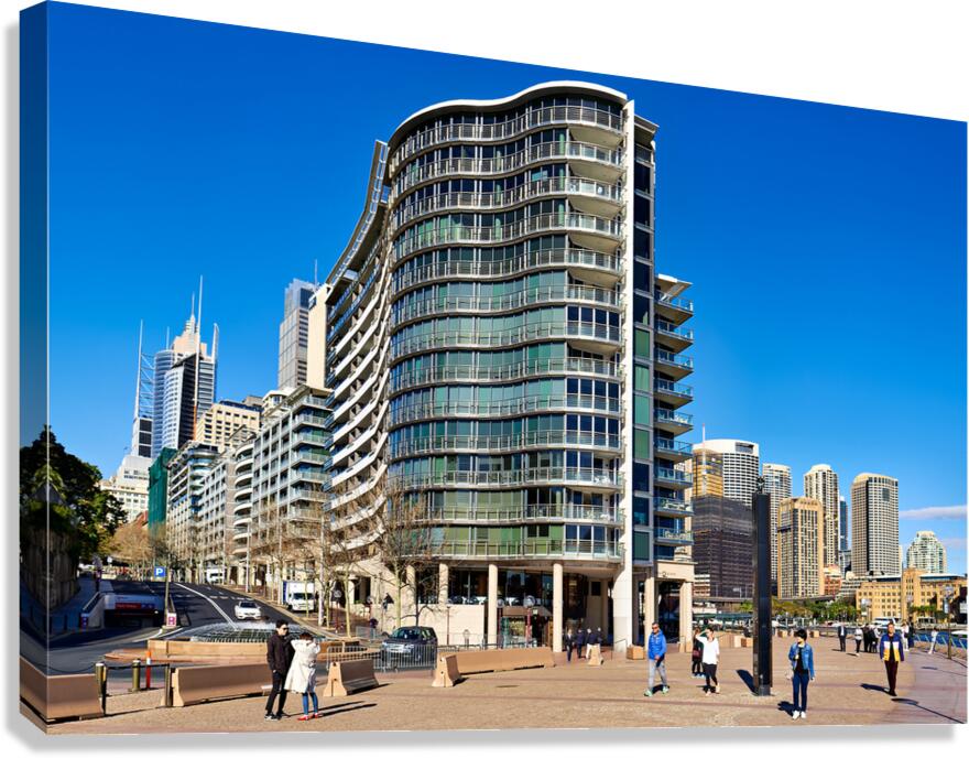 Modern curved building with balconies and city skyline. Canvas Print