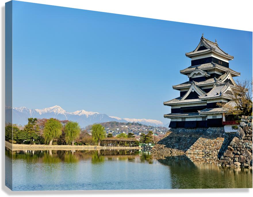 Matsumoto Castle stands beside water with mountains in the dista Canvas Print