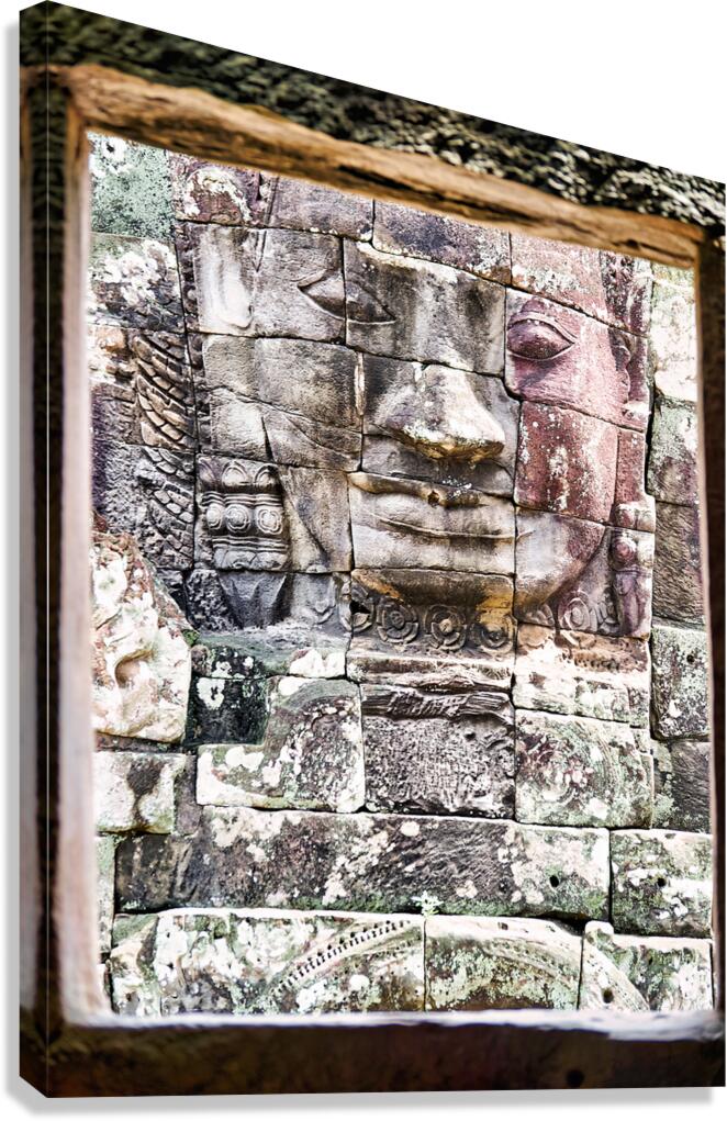 Ancient stone face carving framed in temple window. Canvas Print