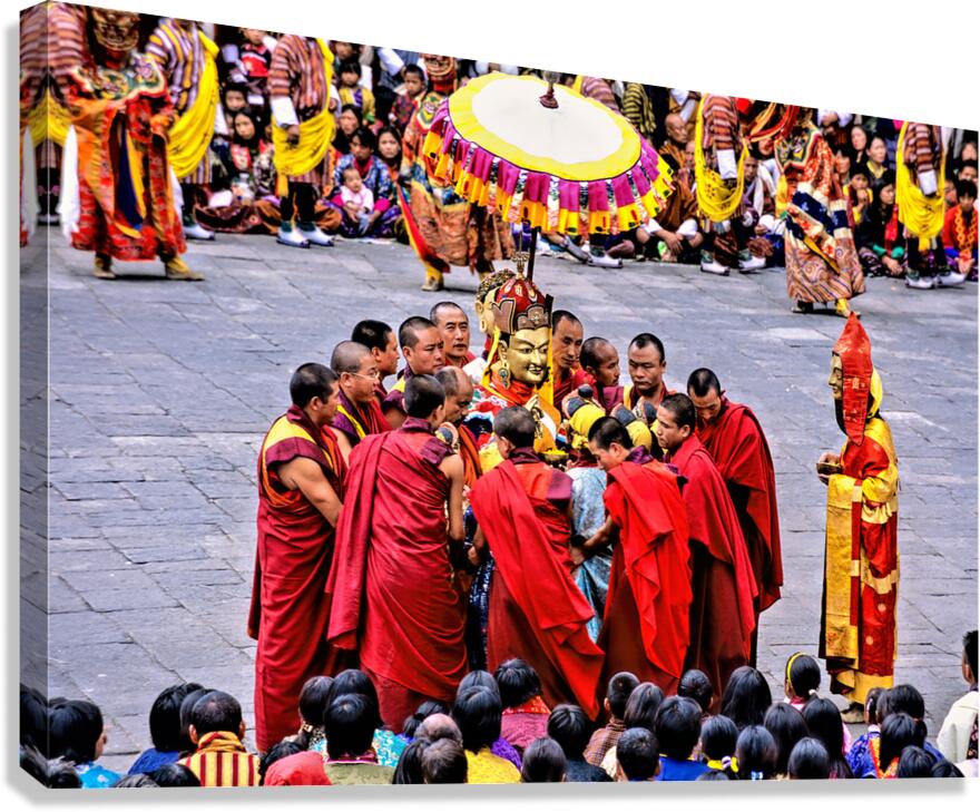 Monks in red robes gathered around a golden statue. Canvas Print