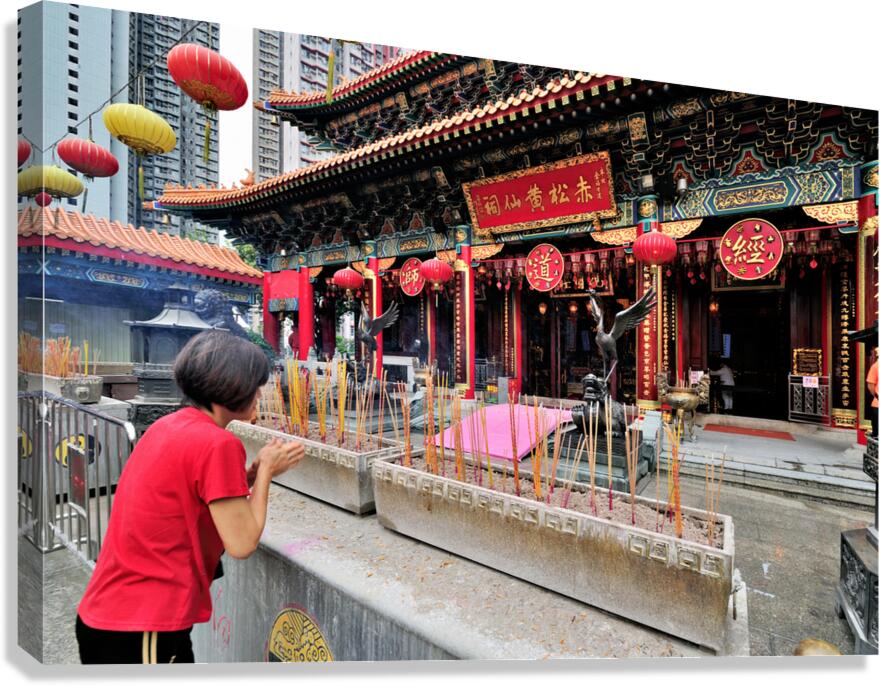 Woman prays with incense at colorful Chinese temple in Hong Kong Canvas Print