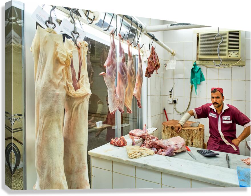 Butcher works in meat market in Dubai with hanging meat Canvas Print