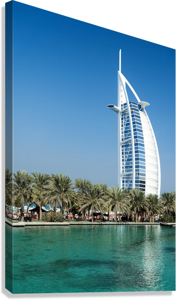 Burj Al Arab hotel stands tall by the water with palm trees Canvas Print