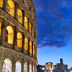 Colosseum at dusk with people walking nearby in Rome