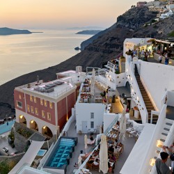Santorini cliffside town with restaurants and sea view at sunset
