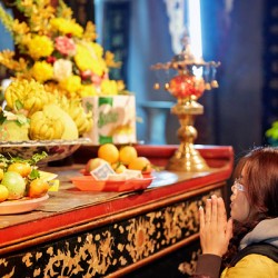 Person offers prayers at altar with fruits in Ho Chi Minh