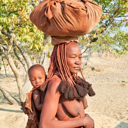 Himba woman carries baby in Kunene region of Namibia