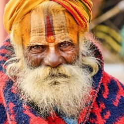 Old holy man in Varanasi wearing bright colors in Uttar Pradesh