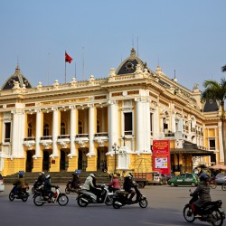 Building in Hanoi with people riding motorbikes in daytime
