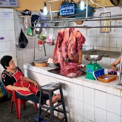 Market scene in Ho Chi Minh City with meat vendor and customer