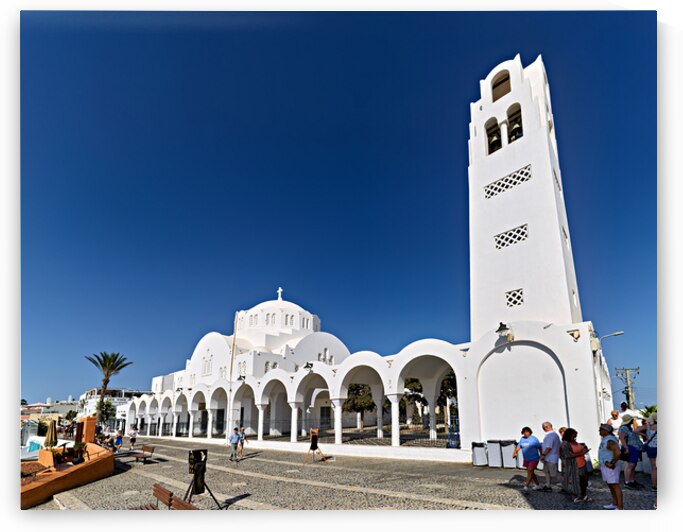 Iconic white church in Santorini under a bright blue sky. by Marco Brivio