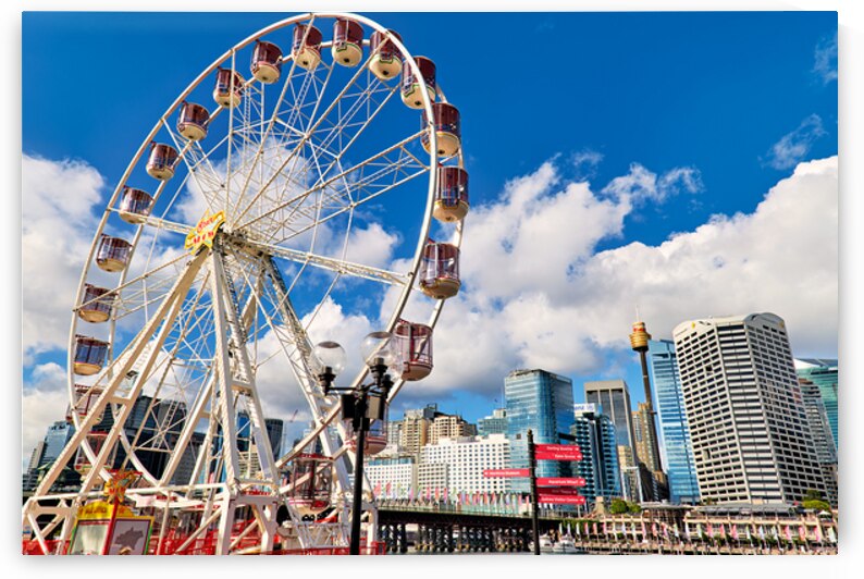 Sydney Ferris wheel with city skyline and blue sky. by Marco Brivio
