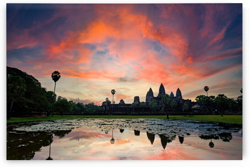 Vibrant sunset sky reflects over ancient Angkor Wat temple. by Marco Brivio
