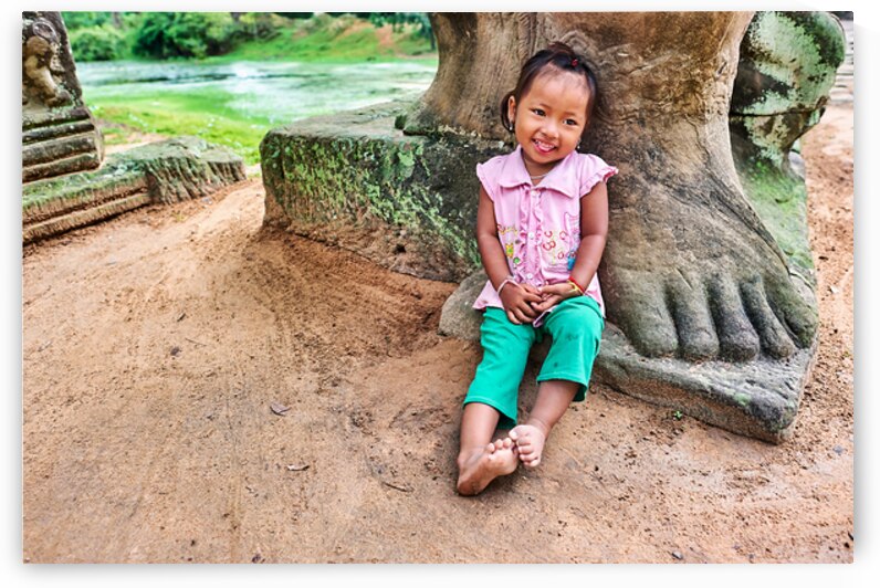 Smiling girl sits by ancient stone structure. by Marco Brivio