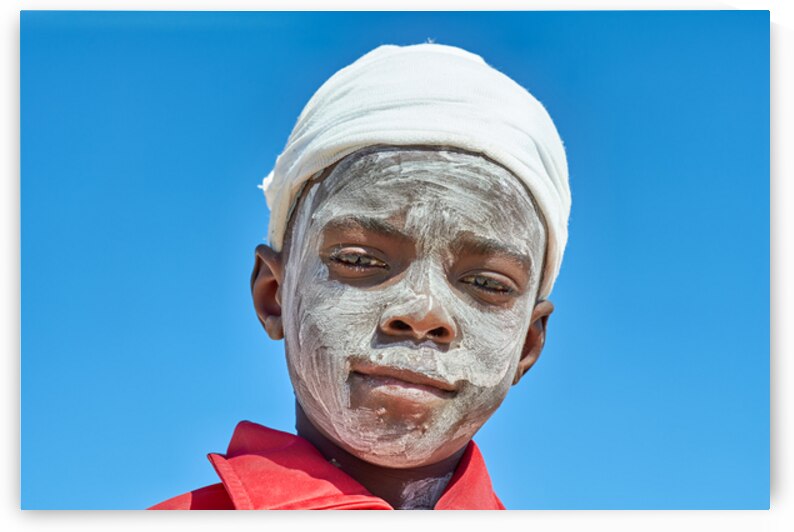 Sad child with a painted face in a village in Damaraland Namibi by Marco Brivio