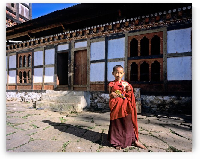 Young monk with toy gun and bread outside a monastery. by Marco Brivio