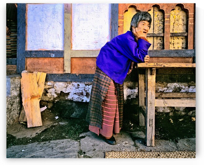 Smiling elderly woman in traditional dress leaning on wooden tab by Marco Brivio