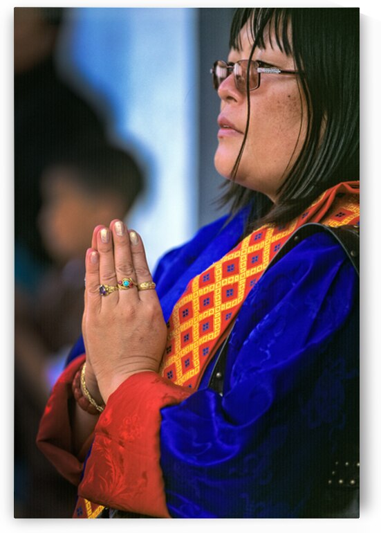 Woman in traditional dress with hands clasped in prayer. by Marco Brivio