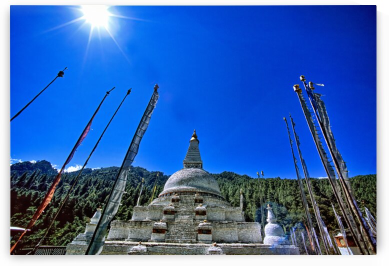 Buddhist stupa and prayer flags against a bright blue sky. by Marco Brivio