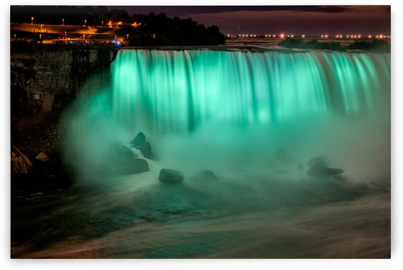 Niagara Falls illuminated green at night with spectators. by Marco Brivio
