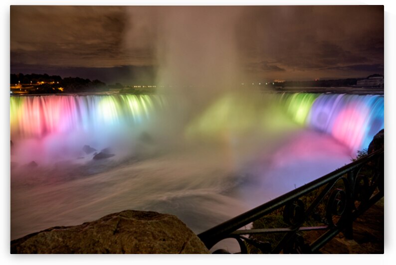 Niagara Falls illuminated at night with colorful lights. by Marco Brivio