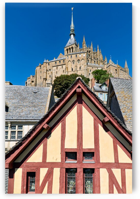 Mont Saint Michel rises above houses in Normandy France on a sun by Marco Brivio