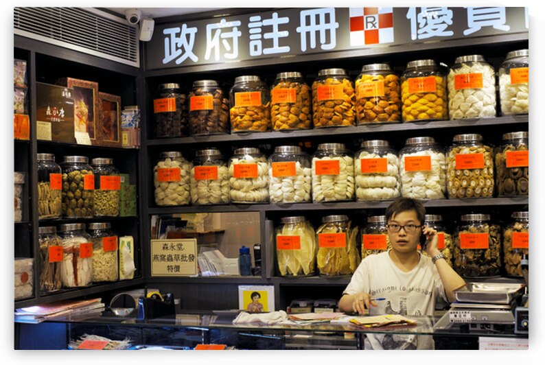 Man talking on phone in traditional herbal shop in Hong Kong by Marco Brivio
