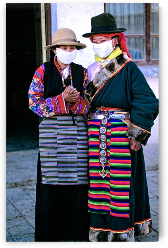 Masked individuals in traditional clothing hold hands in Tibet by Marco Brivio