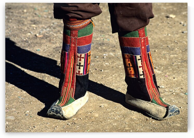 Colorful traditional boots on a person in Tibets landscape by Marco Brivio