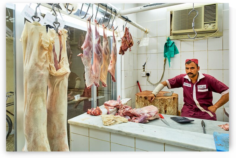 Butcher works in meat market in Dubai with hanging meat by Marco Brivio