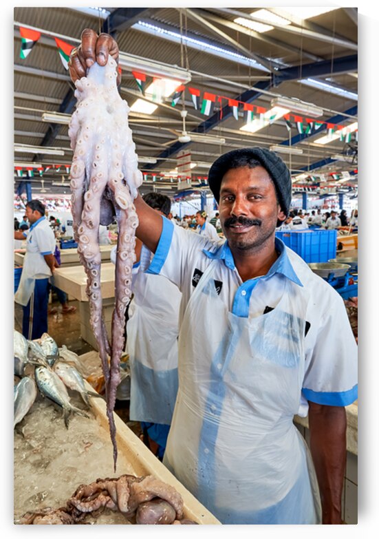 Vendor shows large octopus at fish market in Dubai by Marco Brivio