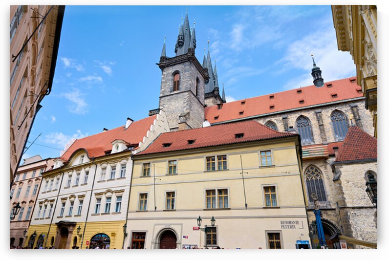 Pragues Týn Church and historic buildings under blue sky. by Marco Brivio