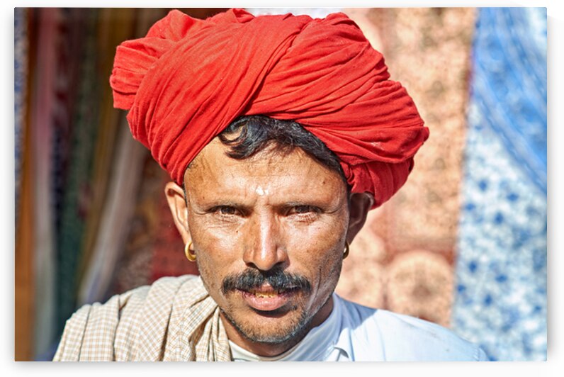 Man in red turban poses in Rajasthans Jaisalmer market street by Marco Brivio