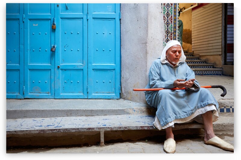 Portrait of a beggar sitting by a blue door in Fez Morocco by Marco Brivio
