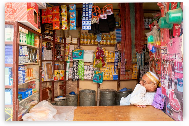 Grocer sleeping in shop in Marrakesh during afternoon hours by Marco Brivio
