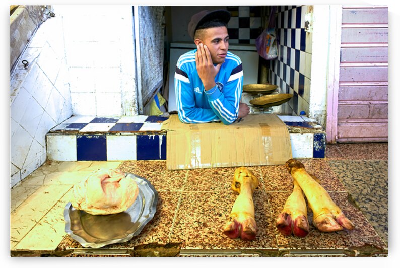 Butcher in Meknes souk interacts with customers during market ho by Marco Brivio