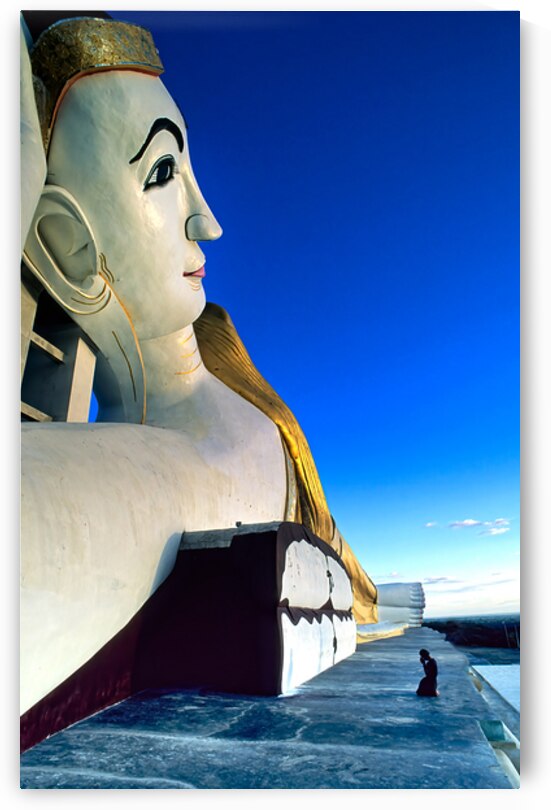 Monywa in Myanmar shows large statue and person in prayer by Marco Brivio